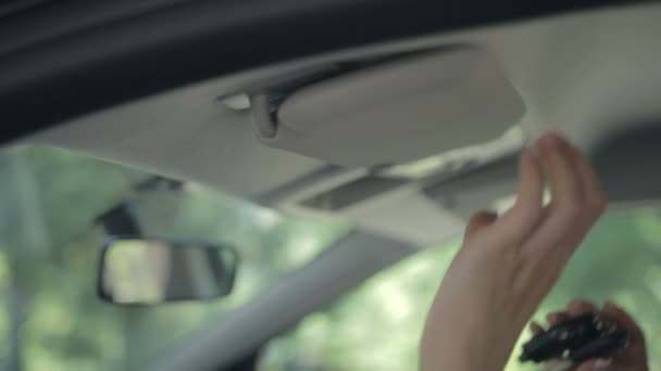 Mulher escondendo chave de ignição no viseira do sol do carro — Vídeo de Stock