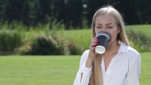 Fröhliche junge Frau trinkt draußen Kaffee — Stockvideo