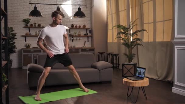 Fit homme pratiquant le yoga avec entraîneur en ligne à l'intérieur — Video