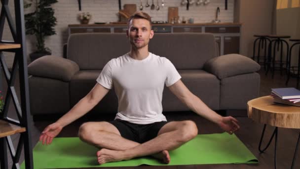 Homme joyeux méditant dans la pose de lotus de yoga à la maison — Video