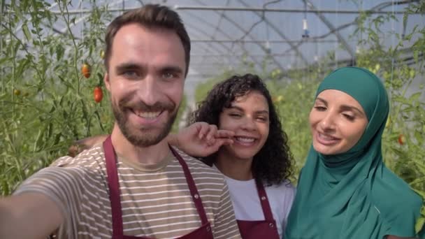 Команда садівників посміхається для селфі в теплиці — стокове відео