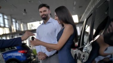 Otomobil galerisinin anahtarlarını alan mutlu araba sahipleri.