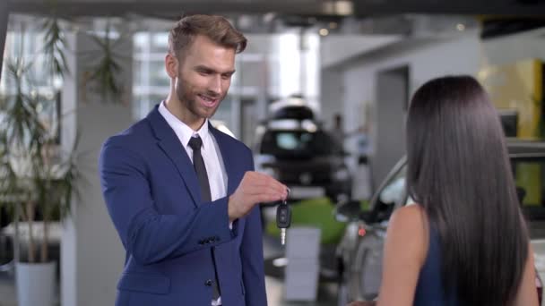 Rivenditore automatico sorridente che dà la chiave dell'automobile al compratore femminile — Video Stock