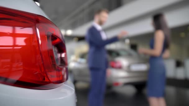 Verschwommener Autohändler übergibt Autoschlüssel an Käuferin — Stockvideo