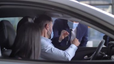 Alınan otomobilin anahtarını alan maskeli iki alıcı.