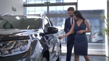 Güzel bir bayan galeride araba açmak için telefon kullanıyor.