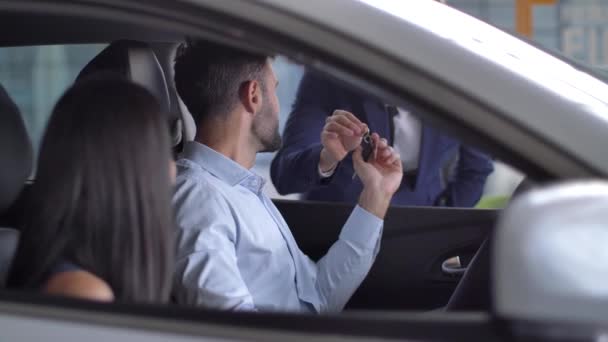 Cuplu bucuros luând cheile în timp ce stăteau în mașină nouă — Videoclip de stoc
