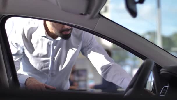 Comprador satisfeito olhando dentro do carro na concessionária — Vídeo de Stock