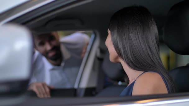 Hermosa joven sentada en coche en la sala de exposición — Vídeo de stock