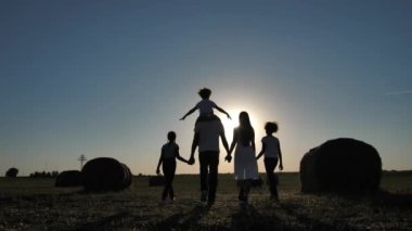 Çok ırklı bir aile gün batımında sahada yürüyor.
