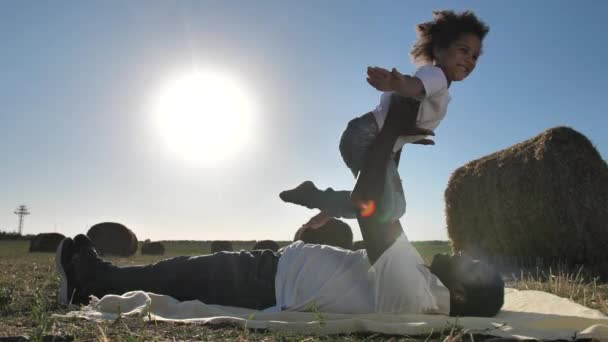 Glad lockig flicka flyger på pappor armar utomhus — Stockvideo