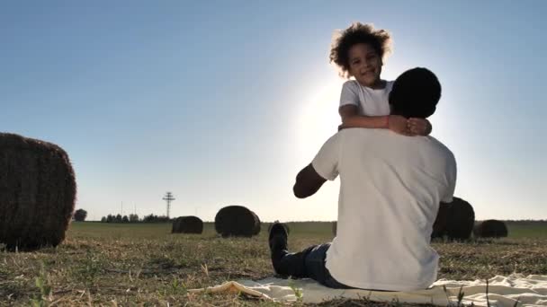 Милая девушка обнимает папу сидя на одеяле на природе — стоковое видео