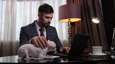Ofis masasında köpek yavrusuyla çalışan saygıdeğer bir adam.