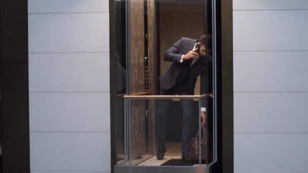 Muž mluví po telefonu při nástupu do hotelového výtahu — Stock video