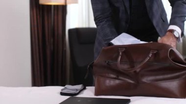 Otel odasından çıkarken bavulunu toplayan adamın elleri.