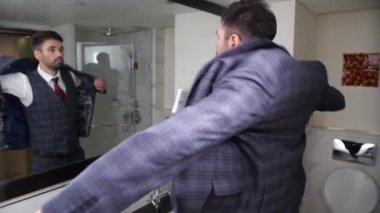 İş adamı otel banyosunda ceket giyiyor.