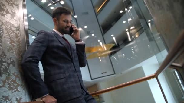 Hombre de negocios alegre hablando por teléfono en cabina de ascensor — Vídeos de Stock