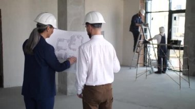 Tasarımcılar apartman planına sahip planları elinde tutuyorlar