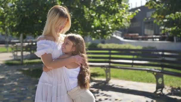 Liefdevolle mam en dochter knuffelen, kussen buiten — Stockvideo