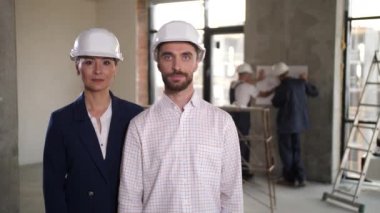 Positive architects posing in renovated apartment