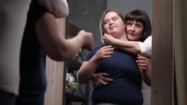 Liebevolle Umarmung von Mutter und behindertem Mädchen vor dem Spiegel — Stockvideo