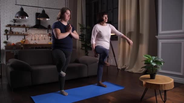 Zakrzywiona niepełnosprawna dziewczyna z mamą uprawiającą jogę w domu — Wideo stockowe