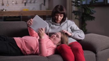 Anne, engelli çocuğunu tablet kullanarak okşuyor.