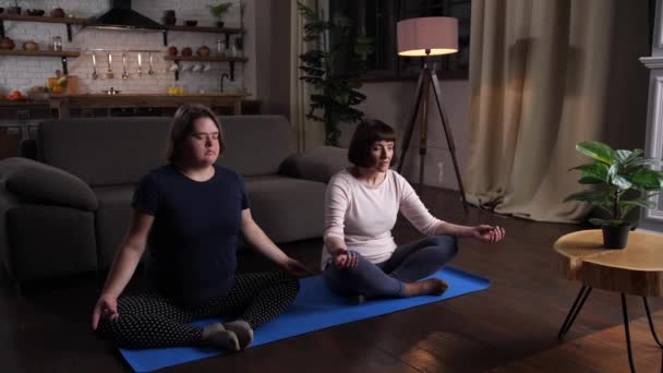 Calm disabled girl with mom practicing yoga indoor — Stock Video