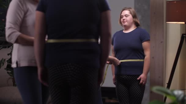 Mother measuring waist of slimming girl by mirror — Stock Video