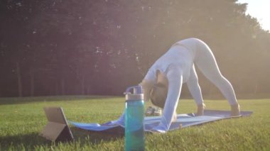 Aktif formda bir kadın güneşli yaz gününde yoga yapıyor.