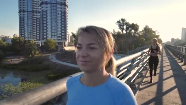 Preciosa rubia corriendo a lo largo del puente de la ciudad — Vídeos de Stock