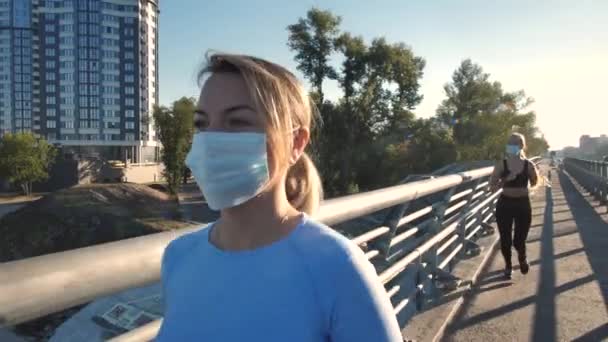 Mascaradas mulheres fitness correndo ao longo da ponte da cidade — Vídeo de Stock