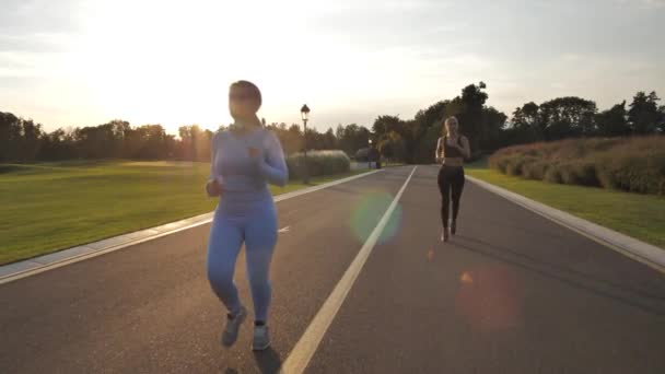 Mujeres jóvenes durante la carrera en el callejón del parque al atardecer — Vídeo de stock