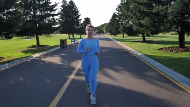 Jeune femme active jogging dans le parc sur une journée ensoleillée — Video