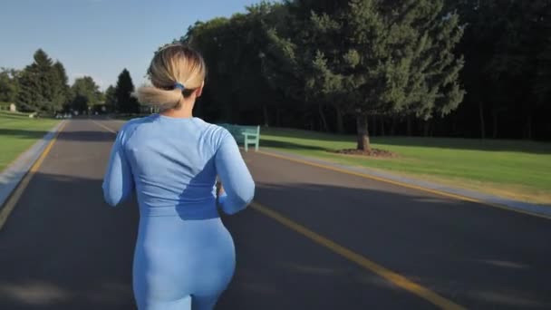 Спортивная молодая женщина бегает по дорожке в парке — стоковое видео