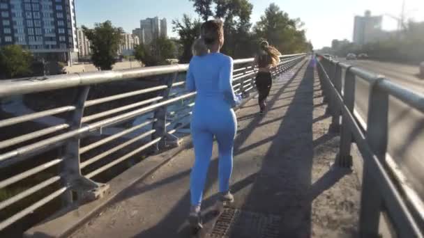 Aktywne kobiety jogging wzdłuż chodnika mostu miejskiego — Wideo stockowe