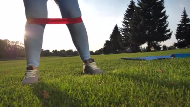 Piernas de mujer deportiva haciendo sentadillas en el césped del parque — Vídeo de stock