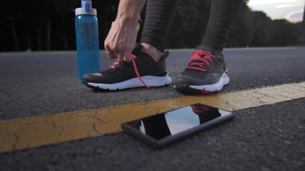 Жінка бігунка зав'язує мережива на кросівки на відкритому повітрі — стокове відео
