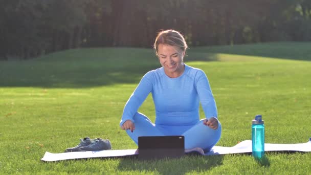 Glad kvinna som gör yoga med online tränare utomhus — Stockvideo