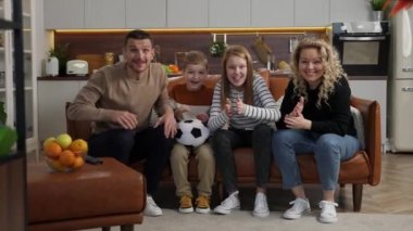 Televizyonda futbol izleyen neşeli sağır ve dilsiz aile.