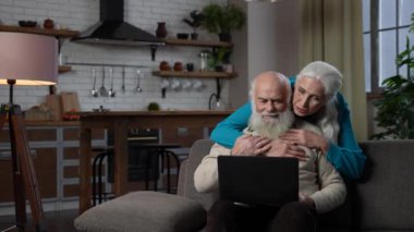 Video araması için dizüstü bilgisayar kullanan sevecen yaşlı çift