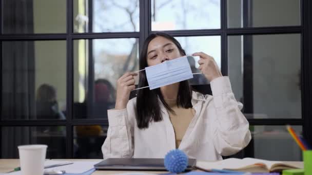 Giovane donna asiatica mettendo su maschera in ufficio — Video Stock