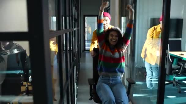 Joyful mixed race woman riding chair in corridor — Video