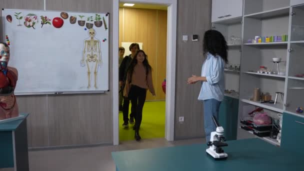 Female teacher greeting pupils entering classroom — Stock Video