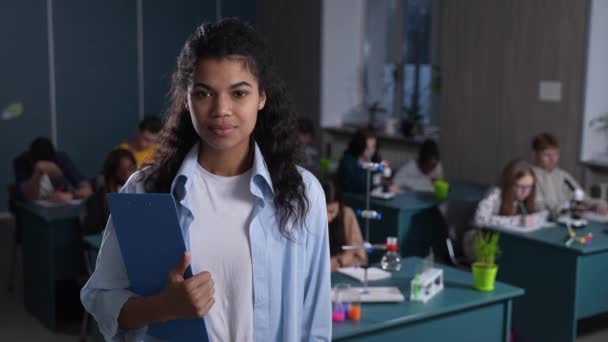 Leende blandras lärare poserar i klassrummet — Stockvideo