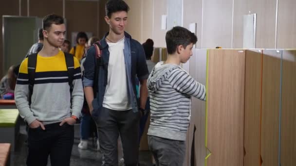 Lång mobbare knuffar klasskamrat i skolans omklädningsrum — Stockvideo