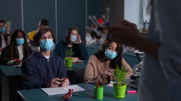 Студенты в масках, изучающие химию — стоковое видео