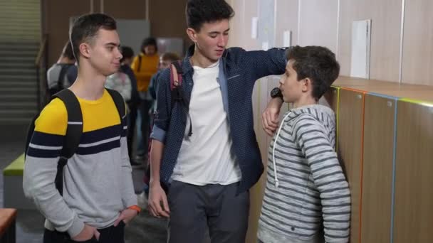 Bullies scoffing boy standing by school locker — Stock Video