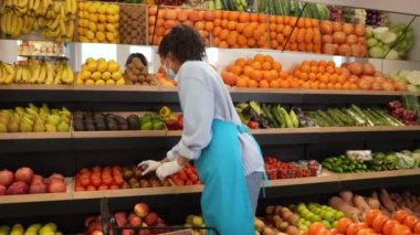 Süpermarkette raflarda çalışan maskeli kadın.