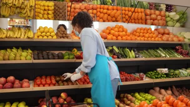 Женщина в маске работает на полках в супермаркете — стоковое видео